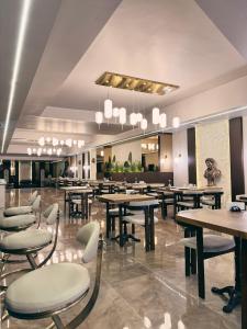 a restaurant with wooden tables and white chairs at Alberello Otel in Kütahya