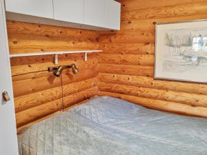a bed in a room with wooden walls at Holiday Home Eskola by Interhome in Lahdenperä +13 photos