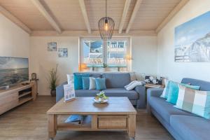 a living room with a blue couch and a table at Ferienhaus Stockente in Dagebüll