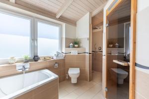 a bathroom with a tub and a toilet and a sink at Ferienhaus Stockente in Dagebüll +20 photos