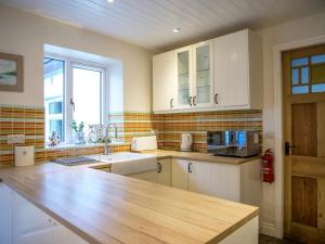 a kitchen with white cabinets and a wooden counter top at Orchard House - Dingle Town Centre in Dingle