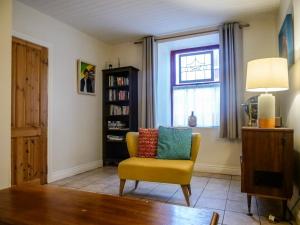 a living room with a yellow chair and a window at Orchard House - Dingle Town Centre in Dingle