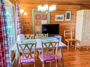 a dining room with a table with chairs and a tv at Holiday Home Kuusiranta by Interhome in Harjula