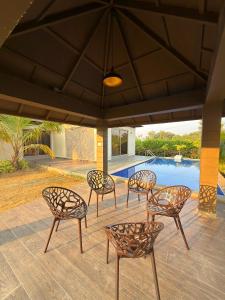 a group of chairs sitting on a patio with a pool at Daksh The Nirvana Retreat in Vitoj
