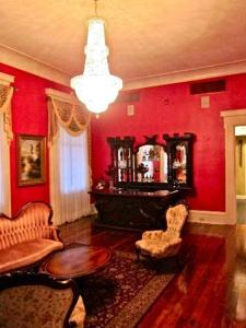una sala de estar con paredes rojas y una lámpara de araña. en Dansereau House, en Thibodaux