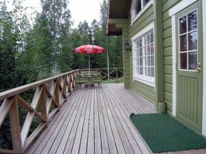 a wooden deck with an umbrella on a house at Holiday Home Villa helmi by Interhome in Holiseva