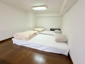 a white room with two beds in it at ハイツロフト102 in Nagasaki