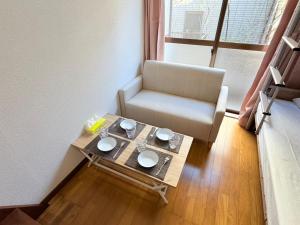 a living room with a table and a chair at ハイツロフト102 in Nagasaki