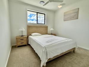a white bedroom with a bed and two night stands at The Calypso Bay in Jacobs Well