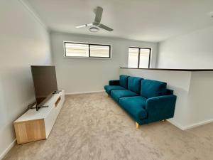 a living room with a blue couch and a tv at The Calypso Bay in Jacobs Well
