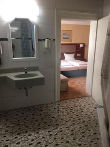a bathroom with a sink and a bedroom with a bed at Hotel Starkenburger Hof in Heppenheim an der Bergstrasse