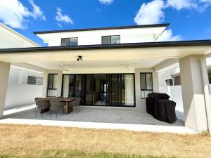 a white house with a patio with a table and chairs at The Calypso Bay in Jacobs Well