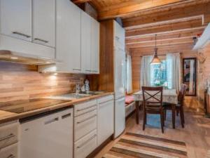 a kitchen with white cabinets and a dining room with a table at Holiday Home Ahonranta by Interhome in Juntusranta