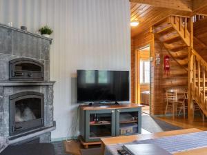a living room with a television and a fireplace at Holiday Home Noukatti by Interhome in Lahdenperä