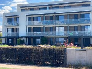 a large white building with balconies and a fence at Balatonra néző, gyerekbarát. in Fonyód