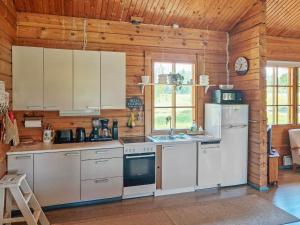 a kitchen with white appliances in a wooden cabin at Holiday Home Annas beach by Interhome in Haminankylä
