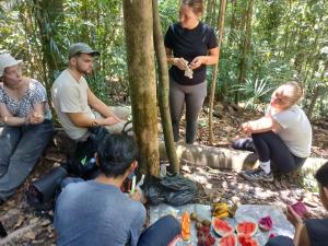 a group of people sitting around a table in the forest at Orangutan Inn in Bukit Lawang
