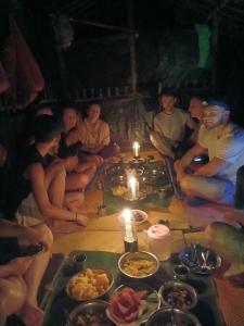 a group of people sitting around a table with food at Orangutan Inn in Bukit Lawang