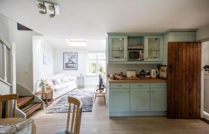 a kitchen with blue cabinets and a living room at The Boathouse in Waldringfield