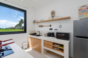 a kitchen with a counter with a microwave and a refrigerator at Villa Sawahku - 2BR Private Villa with Rooftop & Rice Field View in Canggu