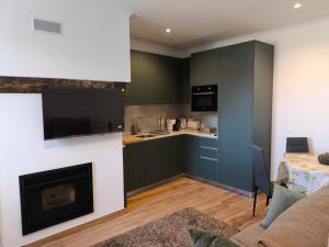 a living room with a fireplace and a kitchen at Casinhas do Penedo in Canelas