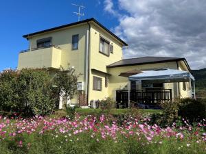 a house with pink flowers in front of it at Yamanobenomichi teku teku in Tenri