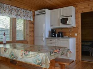a kitchen with a table and a white refrigerator at Holiday Home Rantamaja by Interhome in Kittilä +28 photos