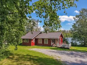 a red cabin on the side of a lake at Holiday Home Pajaranta by Interhome in Hara