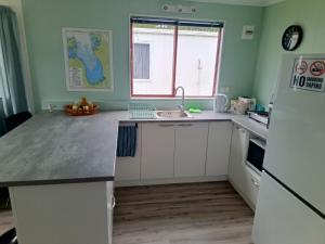 a kitchen with white cabinets and a sink and a window at Coro Coast getaway in Te Puru