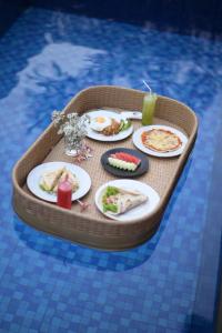 a miniature table with plates of food in a swimming pool at Kubu Daje - Comfortable New Villa in Canggu in Dalung