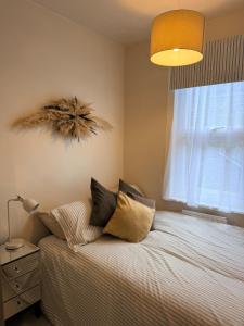a bedroom with a bed with pillows and a window at 2 bed apartment close to beach in Herne Bay