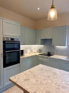 a kitchen with blue cabinets and a marble counter top at 2 bed apartment close to beach in Herne Bay