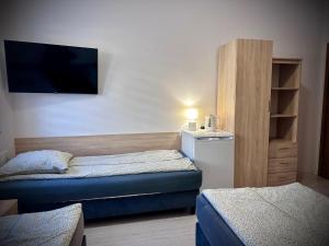 a small room with two beds and a tv at Hostel Sportowa in Płońsk