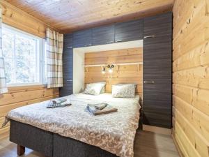 a bedroom with a bed with a wooden wall at Holiday Home Simeoni by Interhome in Äkäslompolo