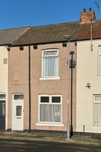 a brick house with white windows and a street light at Suggitt House in Hartlepool