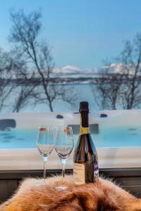 a bottle of wine next to two wine glasses at Robukta Lodge l Jacuzzi l Sauna l Table Tennis in Tromsø