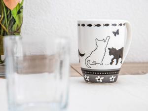 a coffee cup with a cat painted on it next to a glass at Studio Diure 0113 by Interhome in Verbier +20 photos