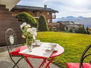 a table with two cups and a vase with flowers at Studio Diure 0113 by Interhome in Verbier