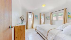 a white bedroom with a bed and a vase of flowers at Luce del sole in Oranjestad +10 photos