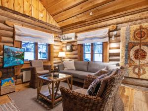 a living room with a couch and chairs in a log cabin at Holiday Home Tunturitorppa by Interhome in Äkäslompolo
