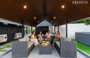 a group of people sitting on a couch under a pavilion at EKOSTAY - Oakwood Chalet in Alibaug