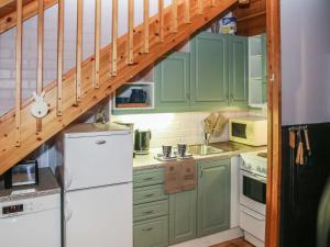 a kitchen with green cabinets and a white refrigerator at Holiday Home Yllästokka 7 by Interhome in Ylläsjärvi