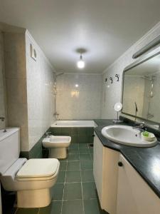a bathroom with a toilet and a sink and a tub at antelias mainroad apartment in An Naqqāsh