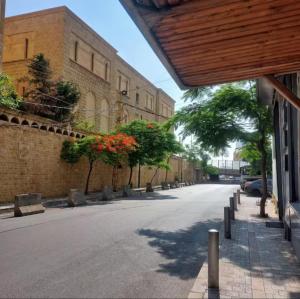 an empty street with trees and a brick building at antelias mainroad apartment in An Naqqāsh