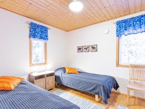 two beds in a room with blue curtains at Holiday Home Aamutähti by Interhome in Äkäslompolo