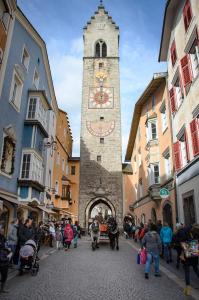 a clock tower in a street with a crowd of people at Nepomuk rooms in Vipiteno