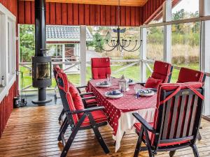 a dining room with a table with red chairs and a fireplace at Holiday Home Villa blomvik by Interhome in Kristenäs