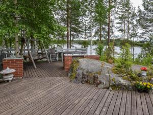 a wooden deck with a table and a rock at Holiday Home Sointukallio by Interhome in Savonlinna