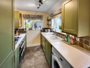a kitchen with green cabinets and a sink at The Painters Cottage in Heckington