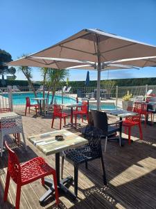 a group of tables and chairs under an umbrella at Logis Hôtel L'Air Marin in Yves